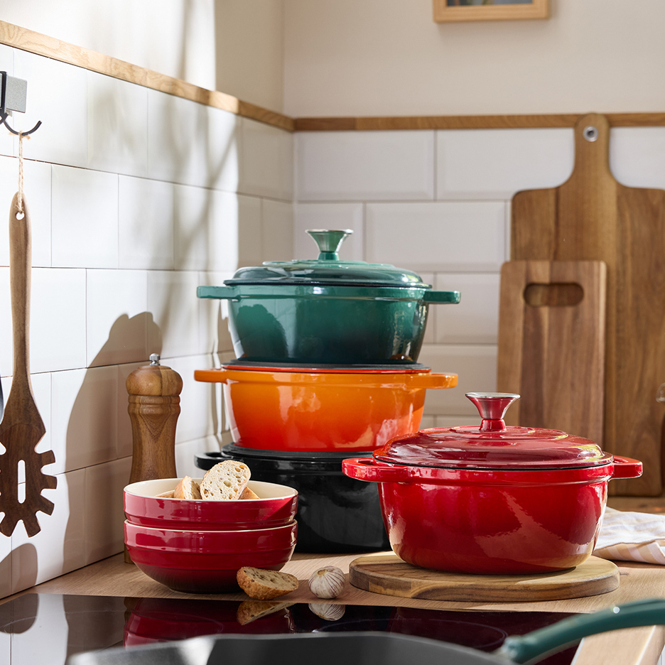 A collection of colorful enameled cast iron cookware, bowls, and kitchen utensils.