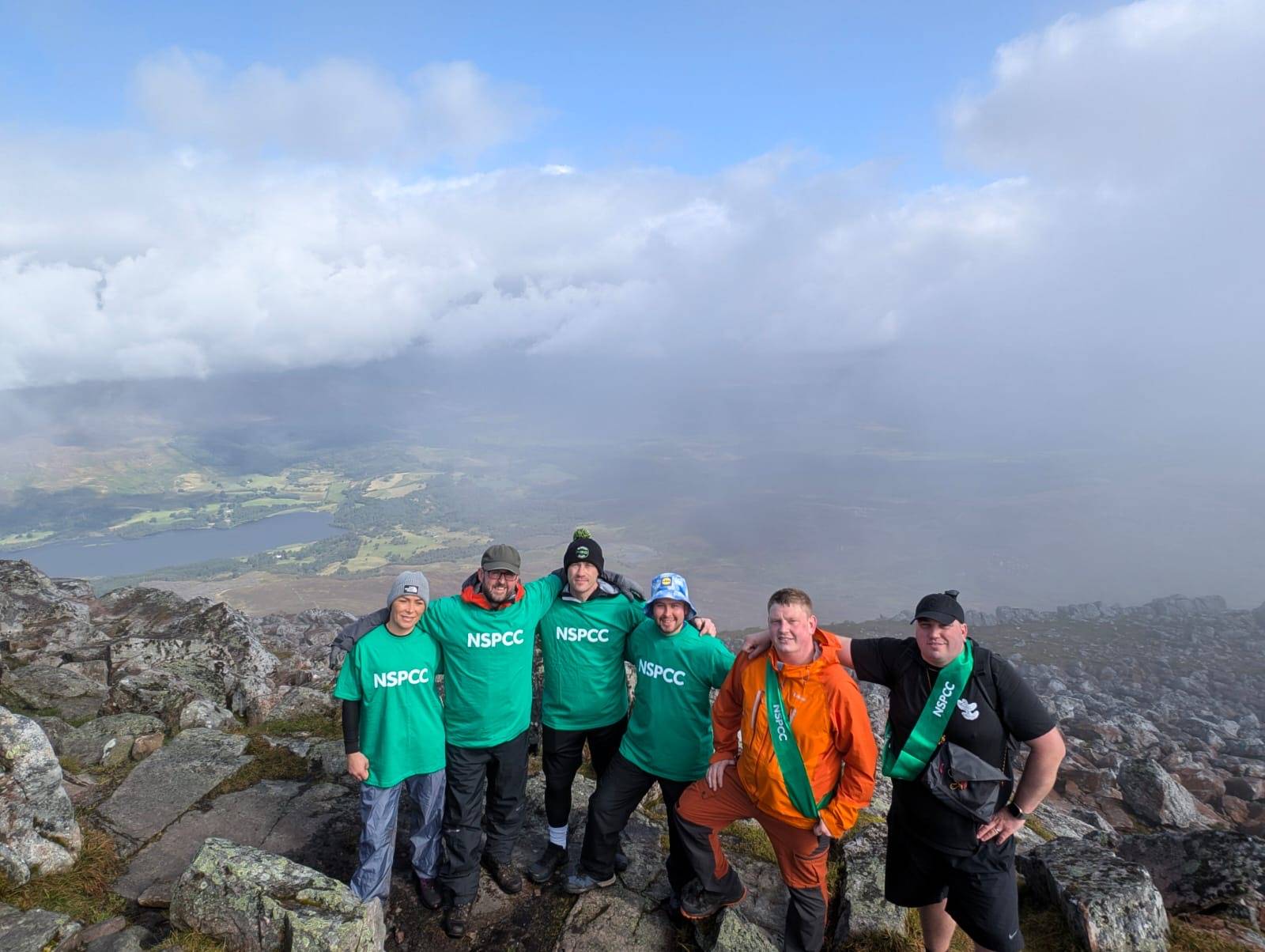 Group in NSPCC shirts on a mountaintop.