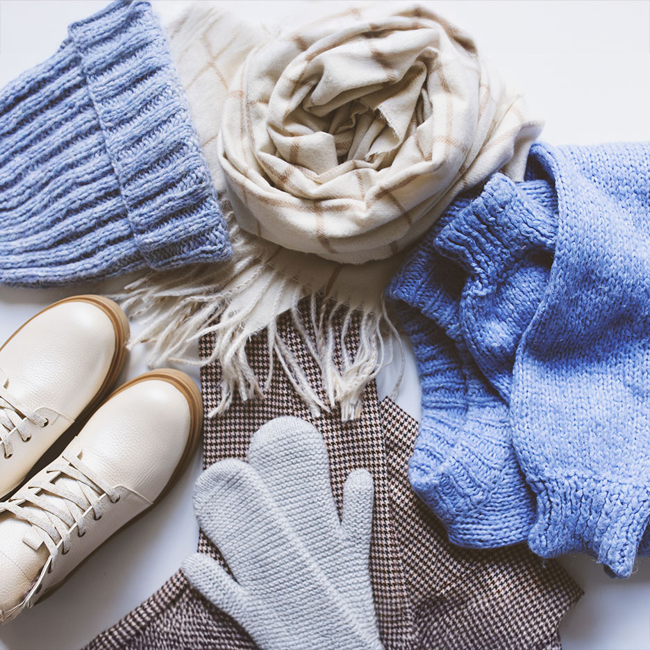 Winter clothing: blue hat and sweater, beige scarf, white boots, and grey mittens.