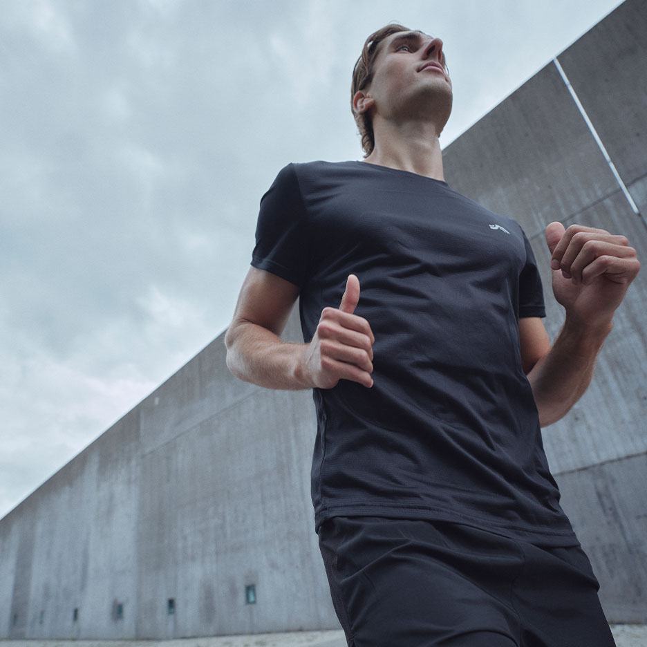 Man in black sports t-shirt and shorts running outdoors.