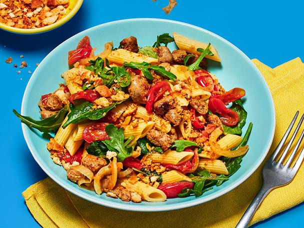 Penne pasta with sausage, rocket and tomatoes.