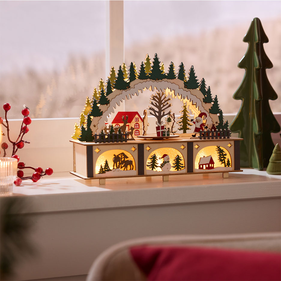 Illuminated wooden Christmas decoration, depicting a winter scene with houses and trees.
