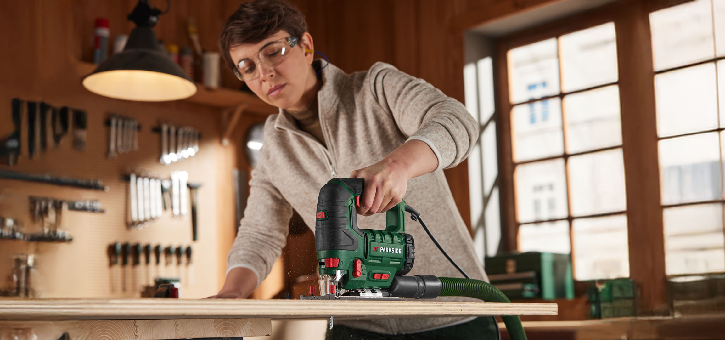 Woman using a Parkside jigsaw to cut wood.