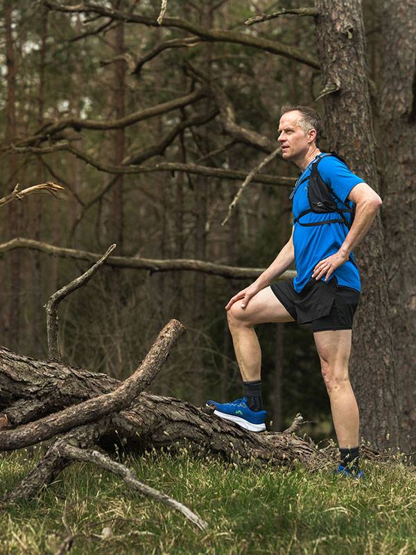 Trail running shoes and apparel in a forest.