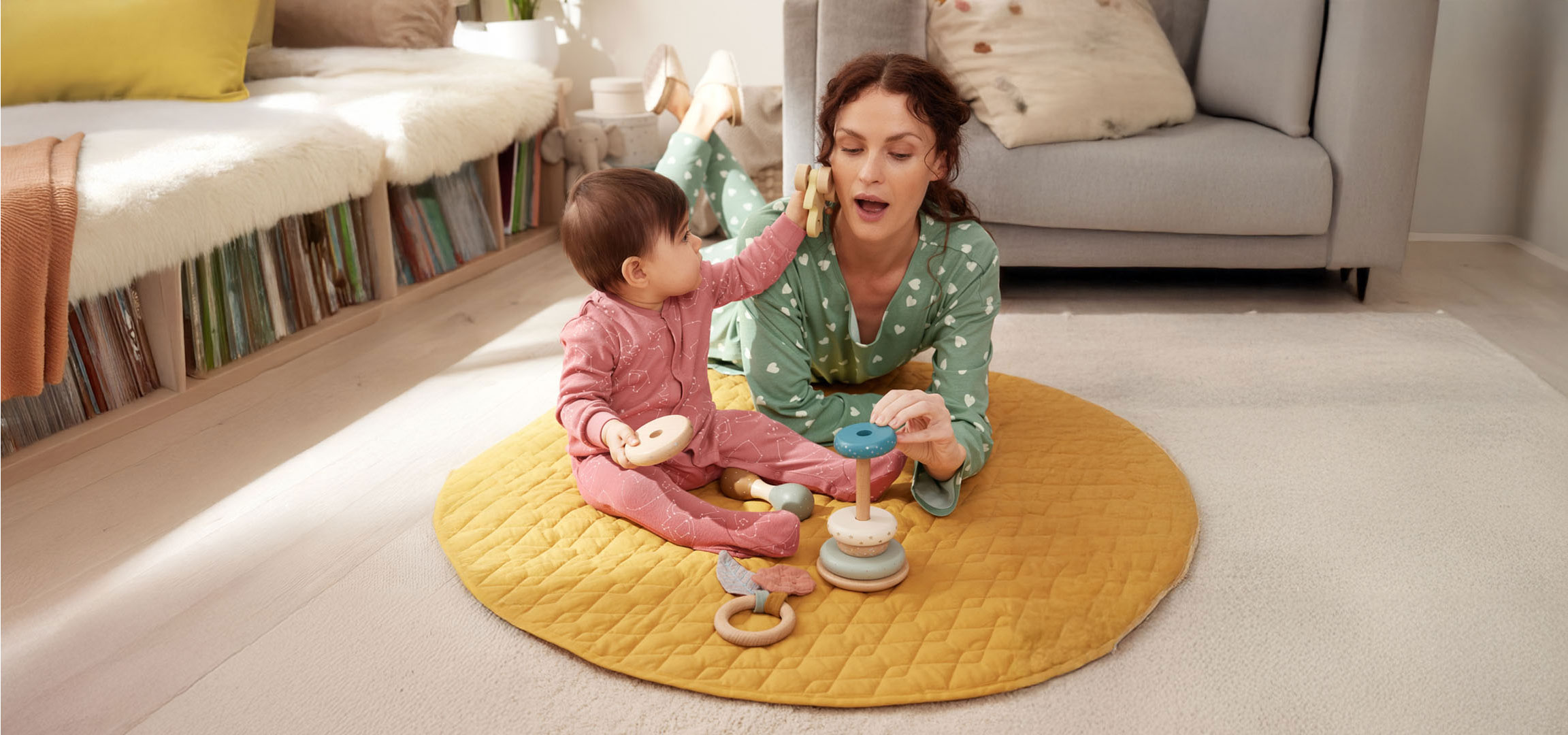 Mother and baby playing with toys on the floor.