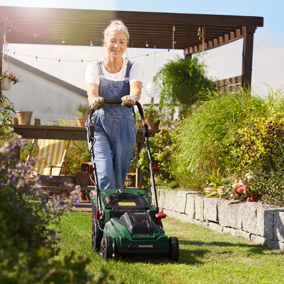 Woman using a Parkside lawnmower in a garden.