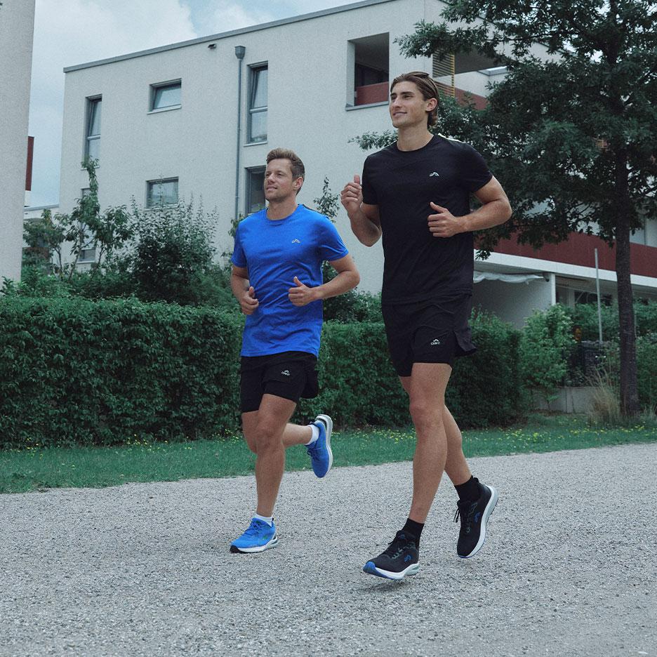 Two men jogging outdoors in black and blue athletic wear.