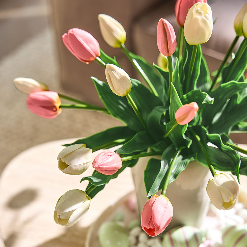 Pink and white tulips in a vase, with Easter eggs on a tray in the background.