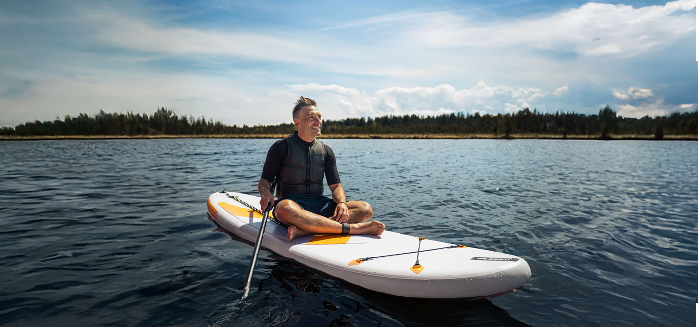 Man paddleboarding on a lake.